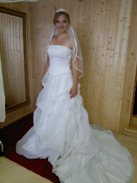 Zufriedene Kundin in einem Brautkleid mit Schleppe und Schleier